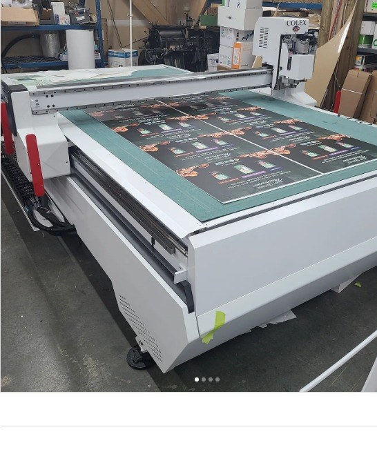 Flatbed cutter shaping a printed rigid display board
